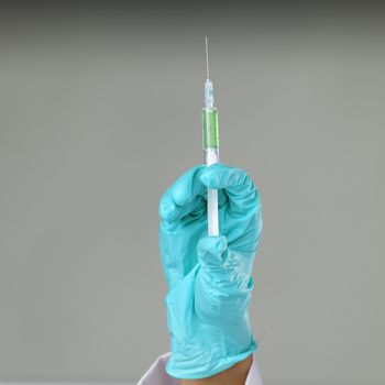 syringe in hand on gray background