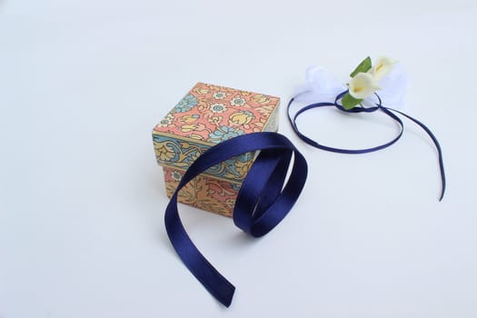 image of closed gift box with blue ribbon and decorative flowers