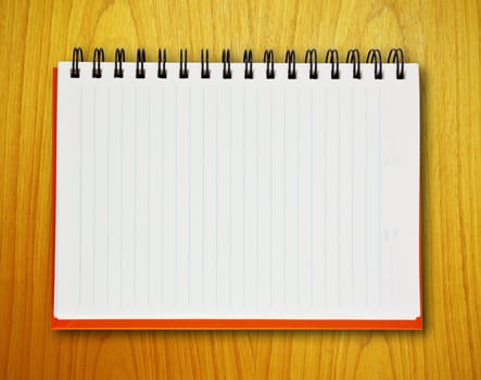 Open orange notebook on wood background
