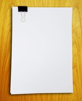 Binder clip and stack of paper on the wood pattern