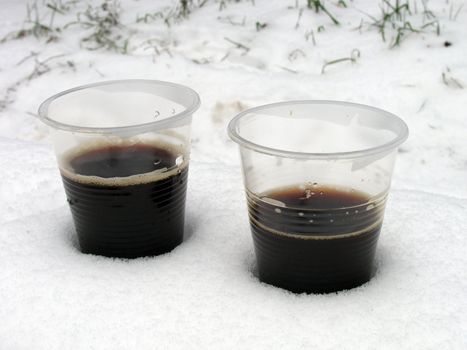 two cups of hot coffee in a snow