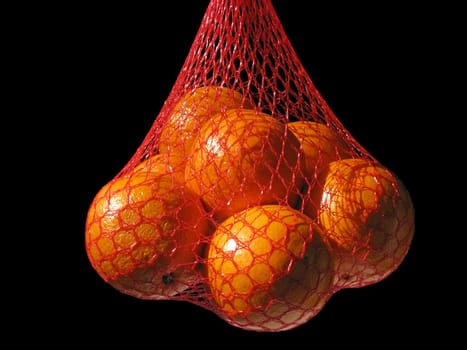 oranges in a string-bag over black