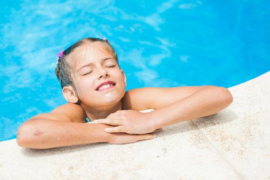 Pretty young smiling girl near a side of the pool