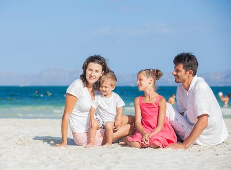 Family of four having fun on tropical beach