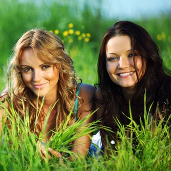 girlfriends lays on green grass and smile