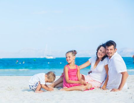 Family of four having fun on tropical beach