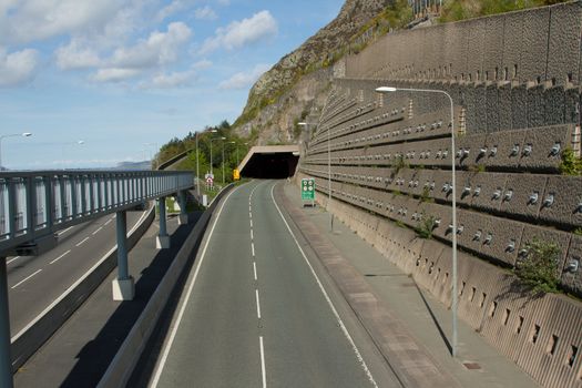 A tunnel on the A55 expressway, North Wales, UK, with a walkway and an engineered retaining wall with steel pins.