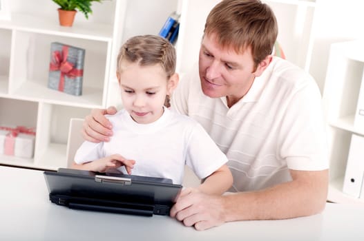 Father and daughter are working together for a laptop at home