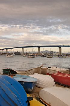 Colorful boats rest along the shore with the Coronado Bridge in the background. Located in San Diego, California.