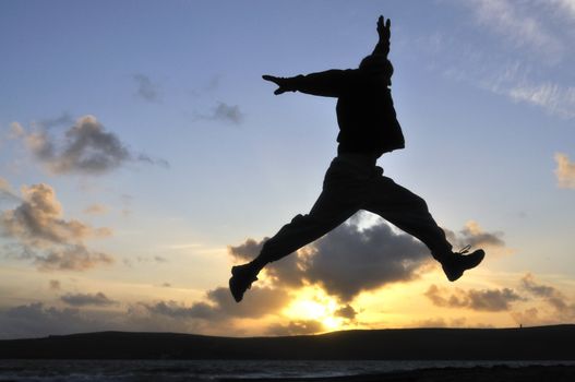 Silhouette of one man jumping over water at the beach.