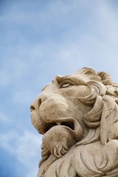 Stone statue of a lion under a nice blue sky