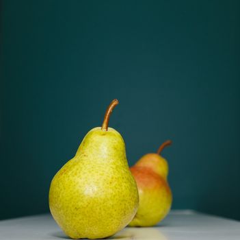 A green Bartlett pear on a green background