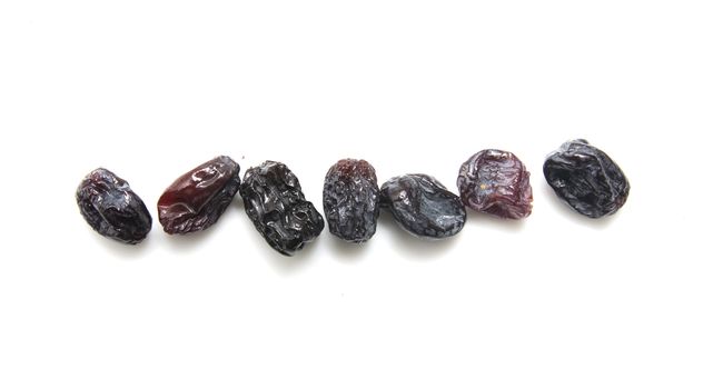 Black raisins set on white background.