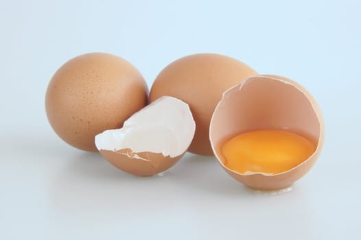 Three eggs with one broken showing the yolk