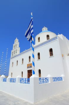 Belfry and cupola of traditional old style white Church of Panagia of Platsani on Caldera Square in village Oia of Cyclades Island Santorini Greece on the blue sky background