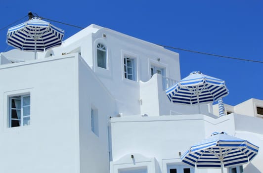 White house with balconies and umbrellas by beautiful weather, Santorini island, Greece