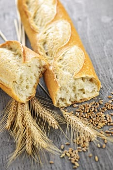 Freshly baked white baguette with wheat ears and grain