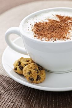 Cappuccino or latte coffee in cup with frothed milk and cookies