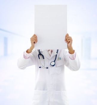 Mixed race female doctor showing blank board on hospital background