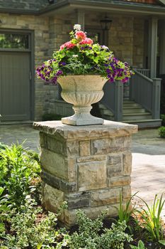 Stone planter with flowers near driveway of house