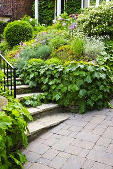 Landscaped garden path with natural stone steps and metal railing