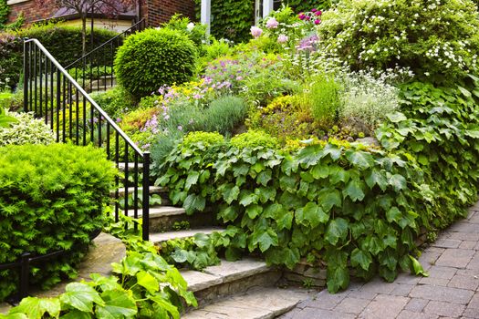 Landscaped garden path with natural stone steps and metal railing