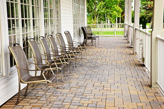 Row of metal chairs on brick patio against windows