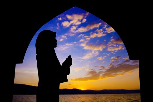 Silhouette of Female Muslim praying in mosque during sunset time
