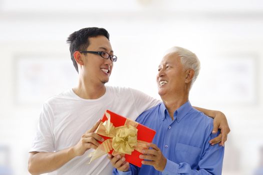 Happy Mixed race Asian father receiving present from his son
