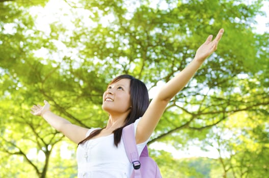 Teen arms raised enjoying the fresh air in green forest.