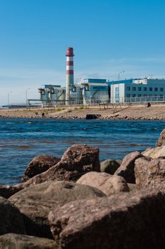 Modern factory, placed on embankment, with stones in front