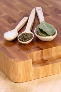 fancy wood spoons on fine wood cutting board with bay leaf ,coarse salt and ground pepper  great cooking ingredients 