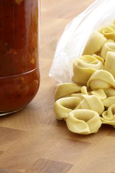 fresh and raw wholegrain tortellini  pasta with tomato sauce jar , the perfect ingredients to make an easy and fast delicious meal.