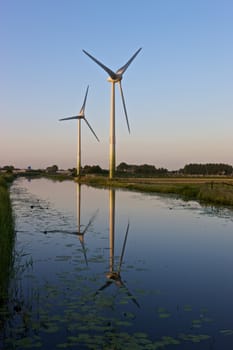 Two modern wind turbines in a Dutch landscape.