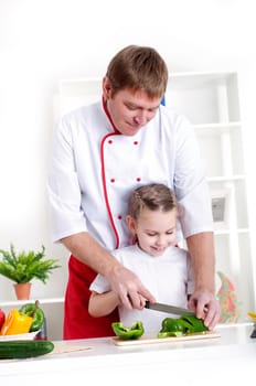 portrait of father and daughter cooking salad together in the kitchen