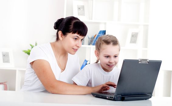 Mom and daughter are working together for a laptop at home
