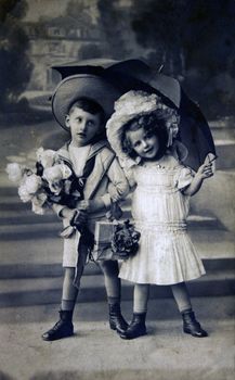 GERMANY - CIRCA 1909: Postcard printed in the Germany shows boy and girl under an umbrella, circa 1909