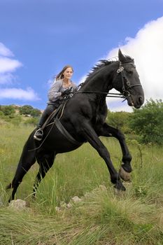 young woman and her black stallion in a field