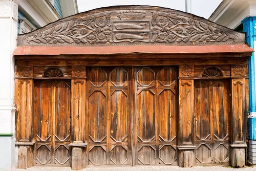 Old closed wooden ornate gate, with symbols on the top