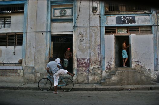 Old colonial house in Havana, few people standing in front , one person on the bike