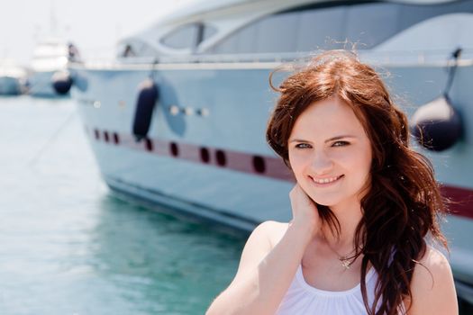 Photo of a young and beautiful girl against the backdrop of yachts in the port