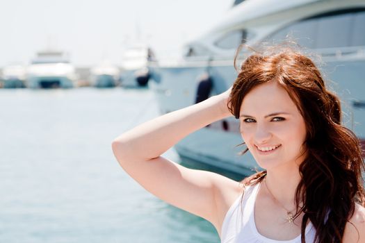 Photo of a young and beautiful girl against the backdrop of yachts in the port