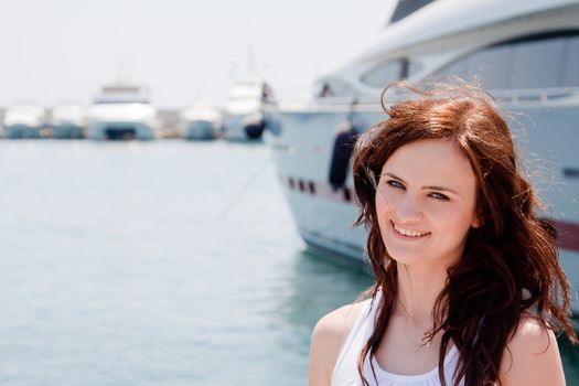 Photo of a young and beautiful girl against the backdrop of yachts in the port