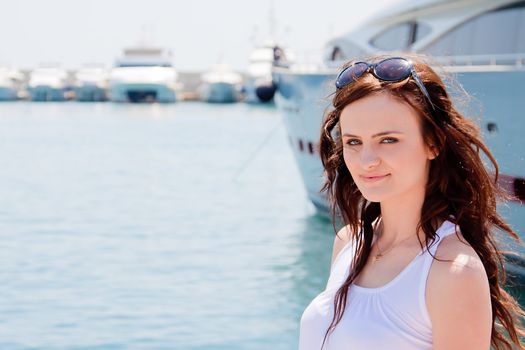Photo of a young and beautiful girl against the backdrop of yachts in the port