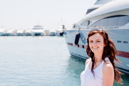 Photo of a young and beautiful girl against the backdrop of yachts in the port