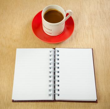 red cup of hot coffee and book on wood background