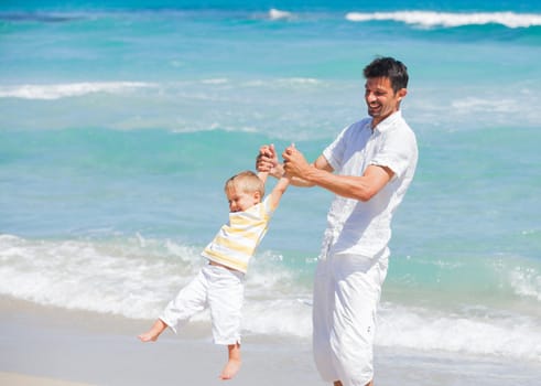 Father and son having fun on tropical white sand beach