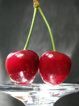 two cherries in light over grey background