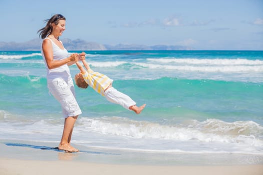 Mother and son having fun on tropical white sand beach