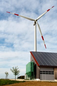 barn covered with solar panels and wind turbine in the background